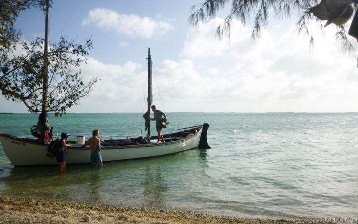 a sailboat rests near a beach on calm blue waters on an outward bound expedition in costa rica